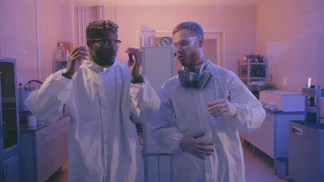 African and caucasian young medical workers putting on safety uniform protecting from biohazard viruses.