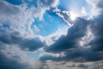 Fluffy rain clouds before rain with sunbeams shining through them.