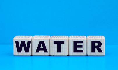 concept word water on wooden cubes on a blue background