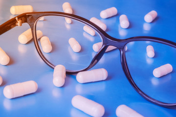 Fototapeta na wymiar Glasses with white pills, eye care concept. Health care. Ophthalmology concept. Eyesight concept.