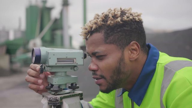 Close up of african survey engineer in construction site use theodolite equipment