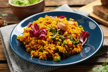 Delicious rice pilaf with chicken and vegetables on wooden table