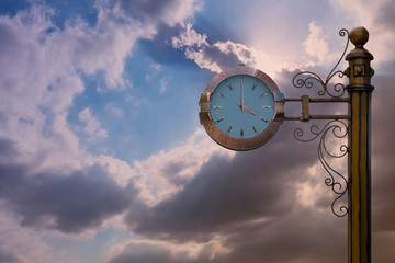 Street clock on sky background. Classic style streeet clock. 4 o'clock.