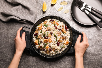 Woman with delicious rice pilaf at grey table, top view