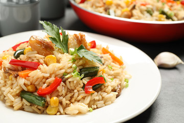 Delicious rice pilaf with chicken and vegetables on black table, closeup