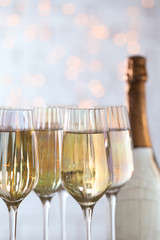 Glasses of champagne and bottle against blurred lights, closeup