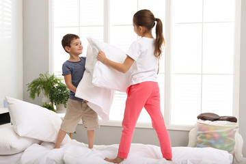 Obraz premium Happy children having pillow fight in bedroom
