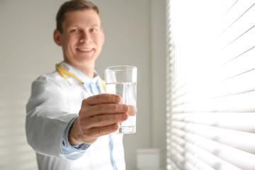 Nutritionist with glass of water near window in office. Space for text