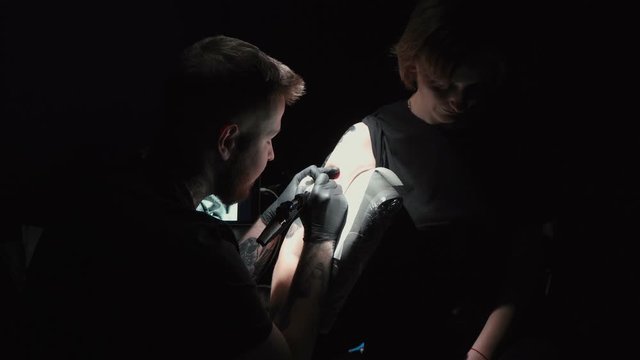 Footage of man doing black tattoo of snake for woman
