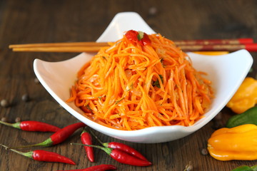 Carrot Korean meat salad with chopsticks on wooden oak table