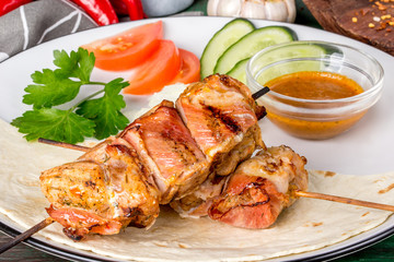 Kebab of turkey in bacon with fresh vegetables.