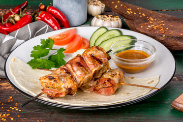 Kebab of turkey in bacon with fresh vegetables.