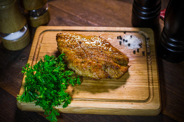Grilled chicken fillet, served on a plate of wood.