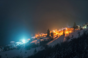Fototapeta na wymiar Night landscape. Winter in Rhodope mountain, Bulgaria, Vrata village. Light in windows of wooden houses. 
