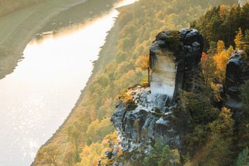 River course of the Elbe in the national park of Saxony in autumn. Rocks with stones and forests in the sunshine in Saxon Switzerland. Sunset on the horizon over the Elbe valley
