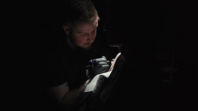 Footage of doing black tattoo of snake on woman in studio