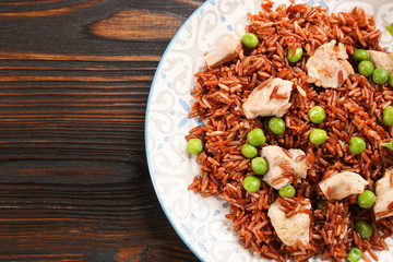 Tasty brown rice with meat and vegetables on wooden table, top view