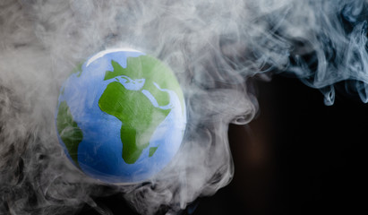 Earth is surrounded by smoke on dark background. Global warming. The concept of disaster