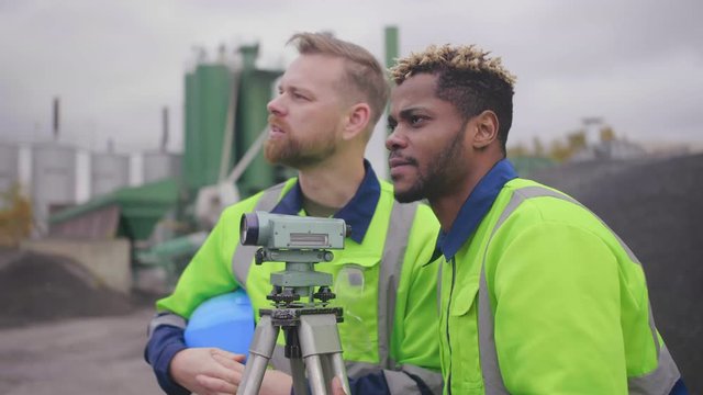 Surveyor engineers making measure on industrial site