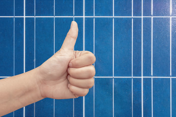 Thumb up on a solar panels background. Photovoltatic power industry.