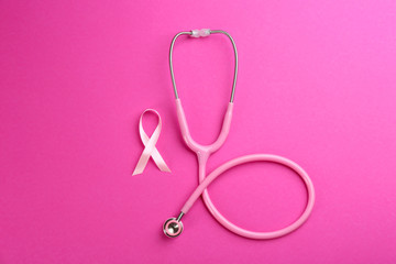 Obraz na płótnie Canvas Pink ribbon as breast cancer awareness symbol and stethoscope on color background, flat lay