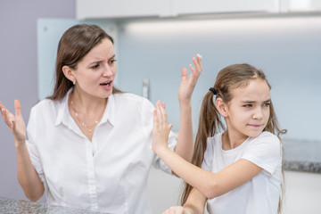 Mother scolds her teenage daughter, girl ignoring her mom and shows stop gesture. Family relationships