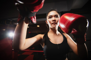 closeup asian woman doing boxing exercise at the gym, she is wearing boxing gloves and hitting in...