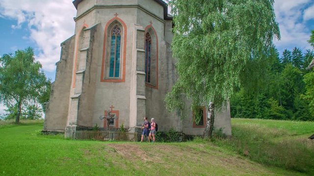 Tourists Hiking by a European Catholic Church in Lese, Slovenia, Tracking Shot