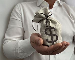 A bag with a dollar sign in the hand of a businessman. A man holds a burlap in his hands. A...