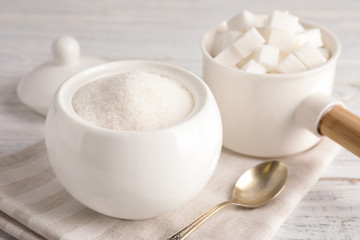 Dishware with sugar on white wooden table