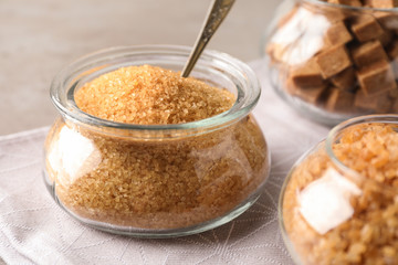 Glass bowl with brown sugar and spoon on table