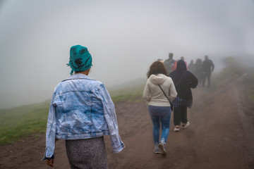 Back view of refugees walk to the border in a cold day under fog