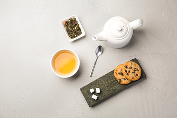 Flat lay composition with cup of hot aromatic tea and cookies on light grey table
