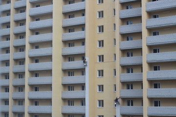 Two male workers are painting the outside of the tall building, By tying yourself to the rope, to job concept.