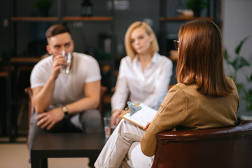 woman psychologist consulting young family consisted only of man and woman in modern office, couple can't get along with each other, troubles in relationships, so male and female visit psychologist