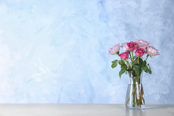 Beautiful roses in glass vase on light grey table. Space for text