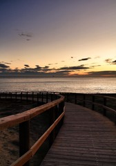 Naklejka na ściany i meble Wooden walkway to the beach at sunrise in Alicante, Spain