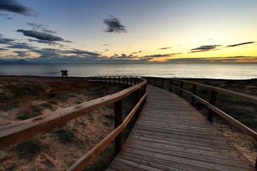 Fototapeta premium Wooden walkway to the beach at sunrise in Alicante, Spain
