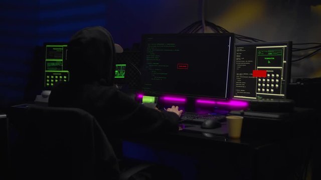 Female hacker writes code in a dark room