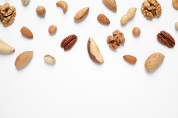 Different delicious nuts on white background, flat lay. Space for text