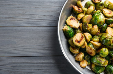 Delicious roasted brussels sprouts on grey wooden table, top view. Space for text
