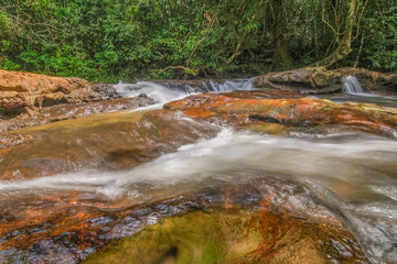 view of stream silky water flowing on rock ground around with green forest background, Pang Sida...