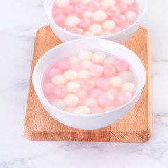 Tang yuan, tangyuan, delicious red and white rice dumpling balls in a small bowl. Asian traditional festive food for Chinese Winter Solstice Festival, close up.