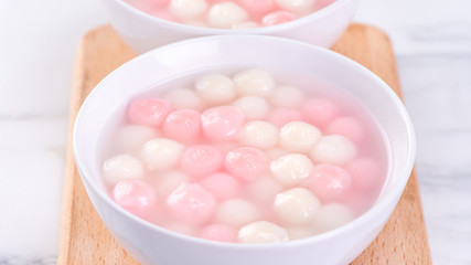 Tang yuan, tangyuan, delicious red and white rice dumpling balls in a small bowl. Asian traditional festive food for Chinese Winter Solstice Festival, close up.