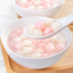 Tang yuan, tangyuan, delicious red and white rice dumpling balls in a small bowl. Asian traditional festive food for Chinese Winter Solstice Festival, close up.