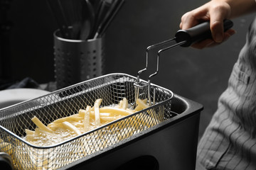 Chef cooking delicious french fries in hot oil, closeup