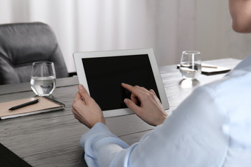 Woman using tablet at desk in office, closeup. Space for design