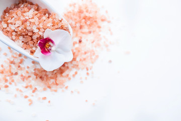 Spa treatments. Himalayan salt and orchid flower in a bath on a white background, top view. Beauty...