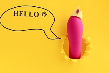 Sex toy for adult, dildo vibrator looking through a hole in the yellow paper with text hello. Funny...