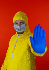 Man in yellow chemical protection suit and face protective mask coronavirus. Gesture stop. Without glasses.